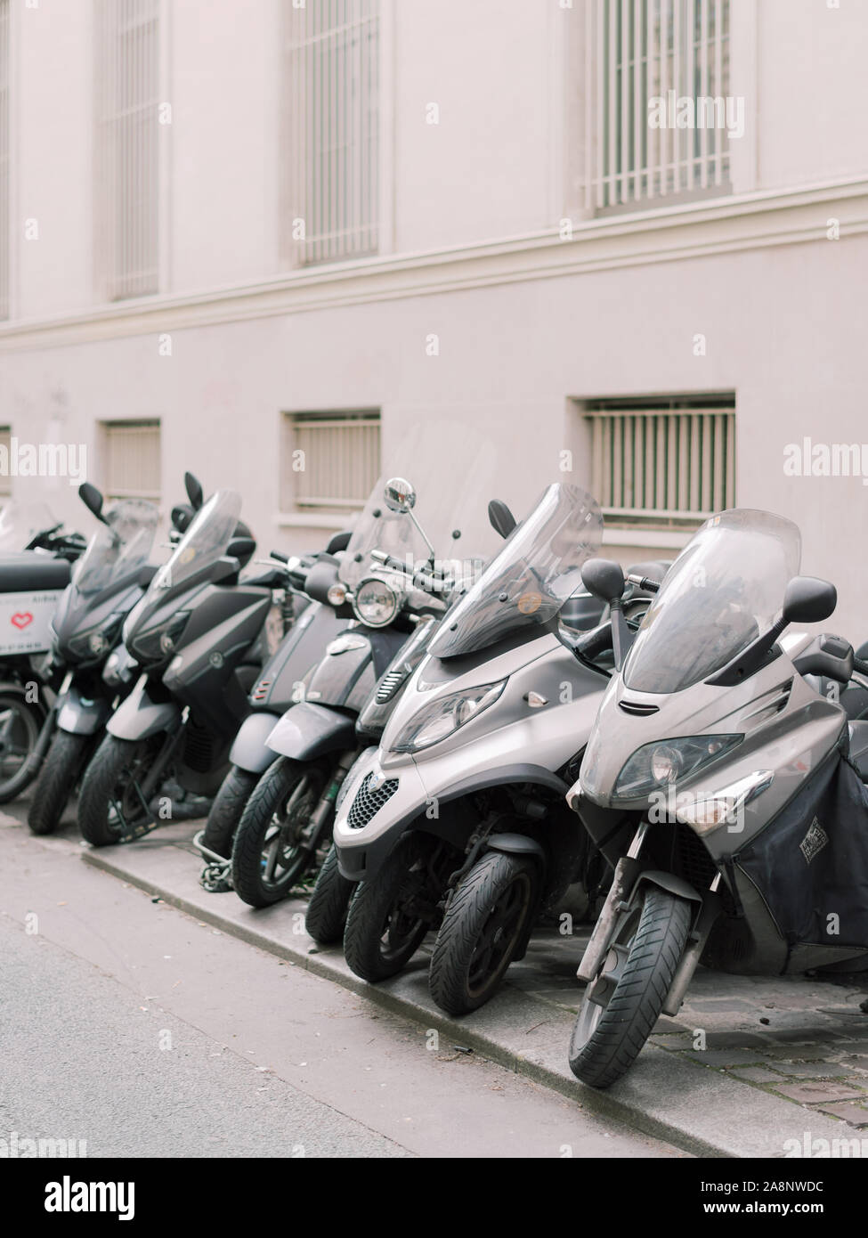 Motociclette e scooters parcheggiato in una fila su un marciapiede a Parigi, Francia Foto Stock