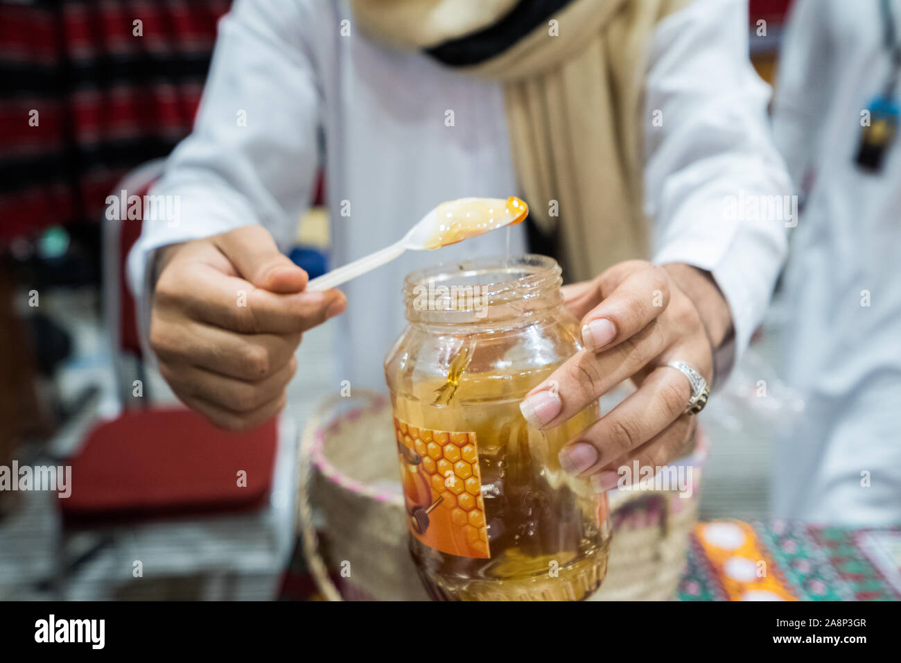 Un uomo è di dare un piccolo cucchiaio di la deluxe di alta qualità miele yemenita Foto Stock