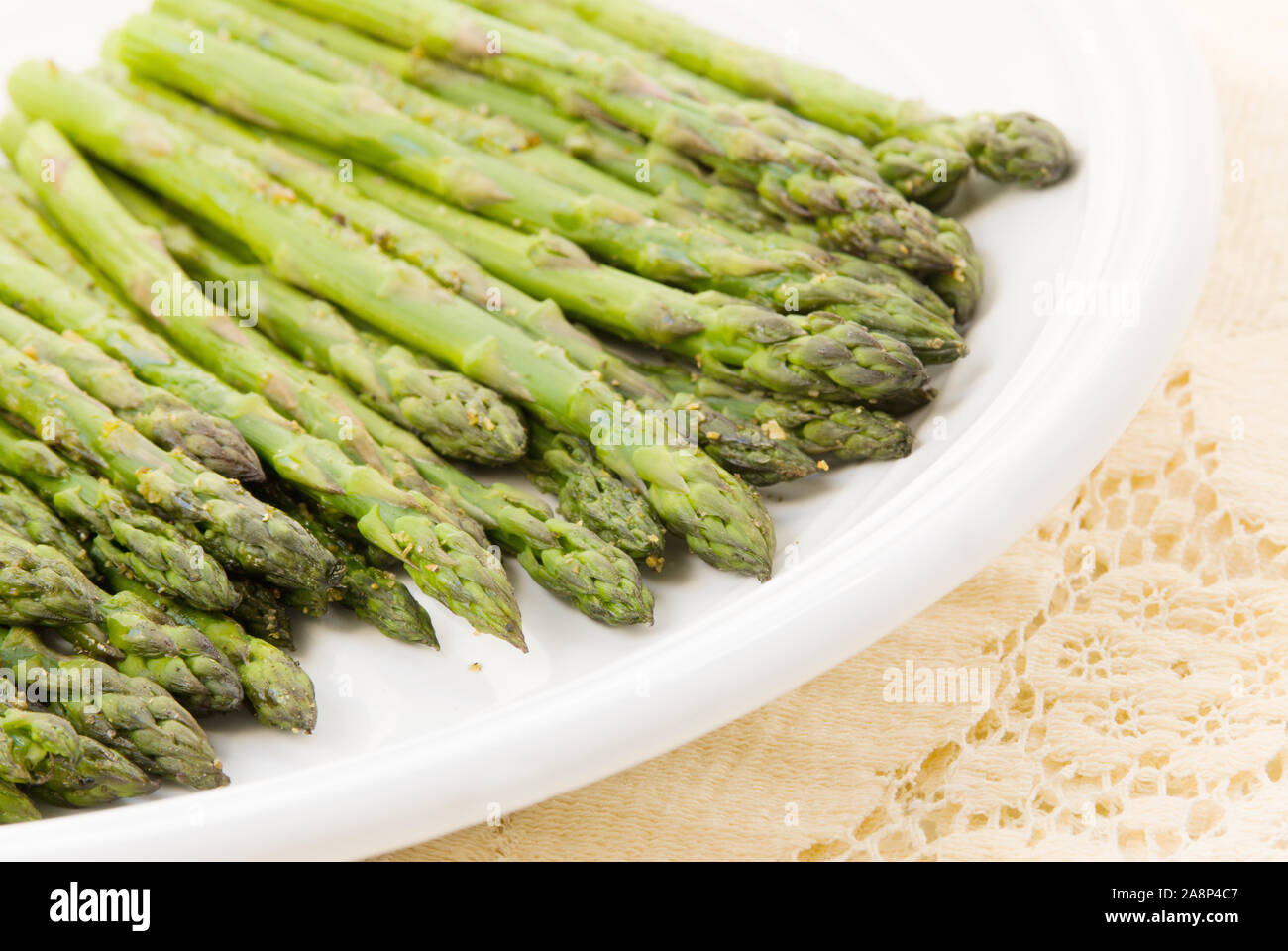 In casa organico asparagi arrosto spears cosparso con sale, pepe, aglio e altre erbe aromatiche. Colpo di luce naturale. Messa a fuoco selettiva. Foto Stock