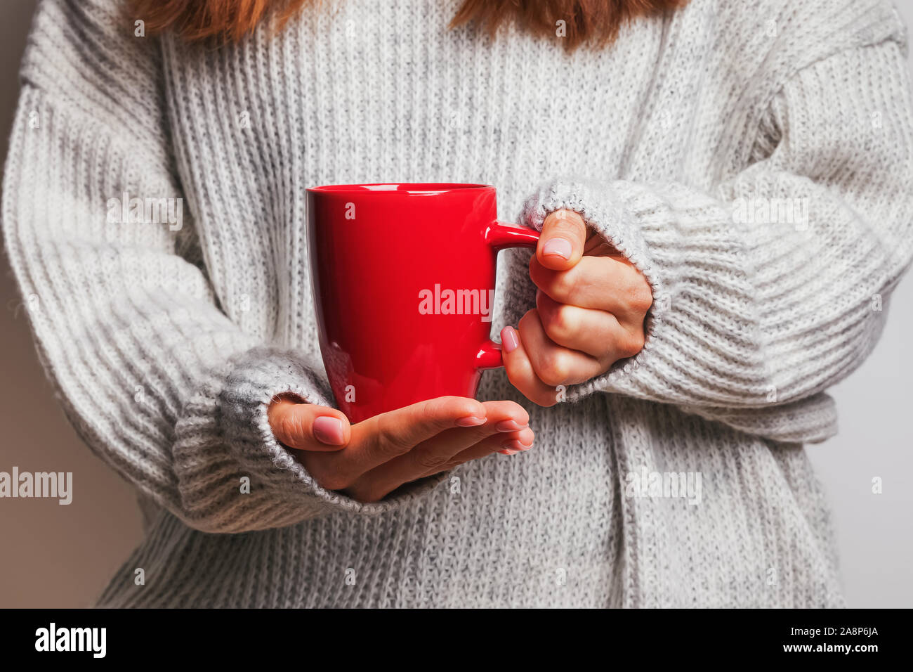 Immagine di una donna di mano che tiene un rosso tazza da caffè Foto Stock