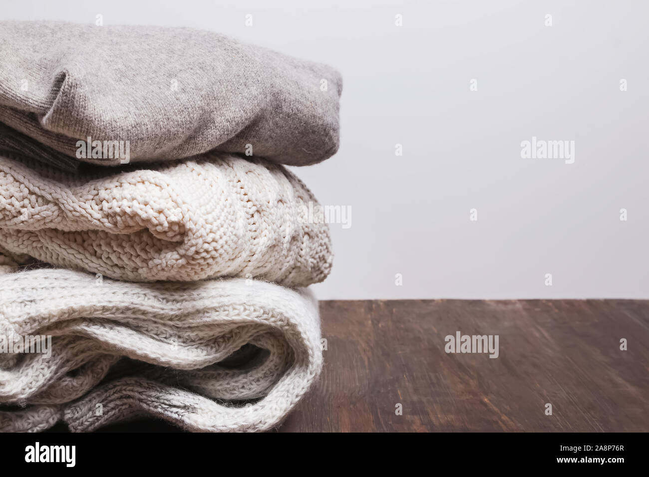 Pila di caldi maglioni a maglia sul tavolo di legno Foto Stock