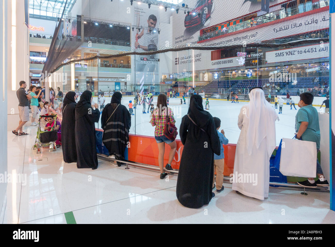 Gli arabi indossando il tradizionale dishdasha bianche vesti la visione di pattinatori, Dubai Ice Rink, centro commerciale di Dubai, Emirati Arabi Uniti Il mall è il più grande del mondo Foto Stock