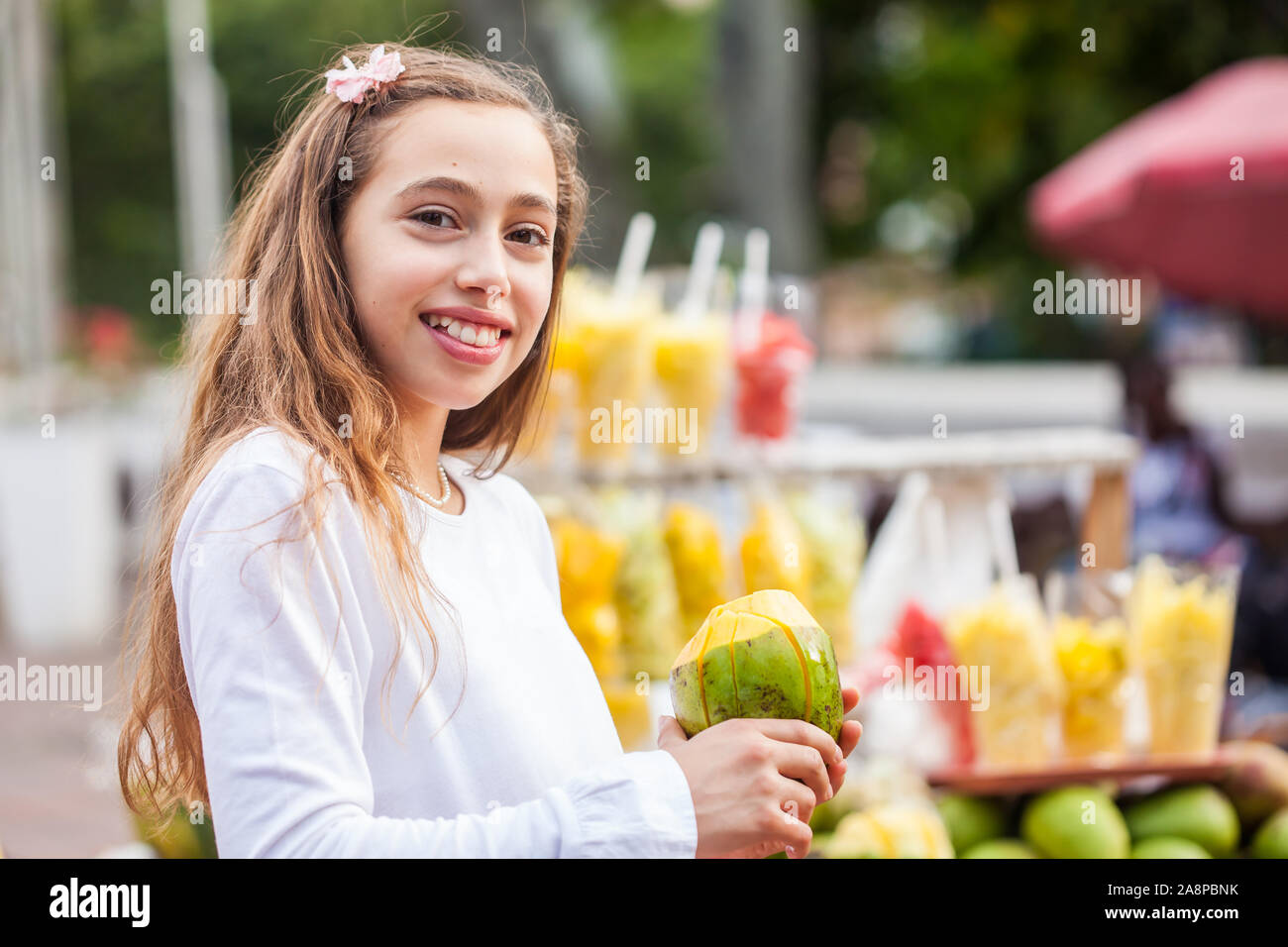 Giovane e bella ragazza al Paseo Piazza Bolivar, nella città di Cali di mangiare frutta tropicale in Colombia Foto Stock