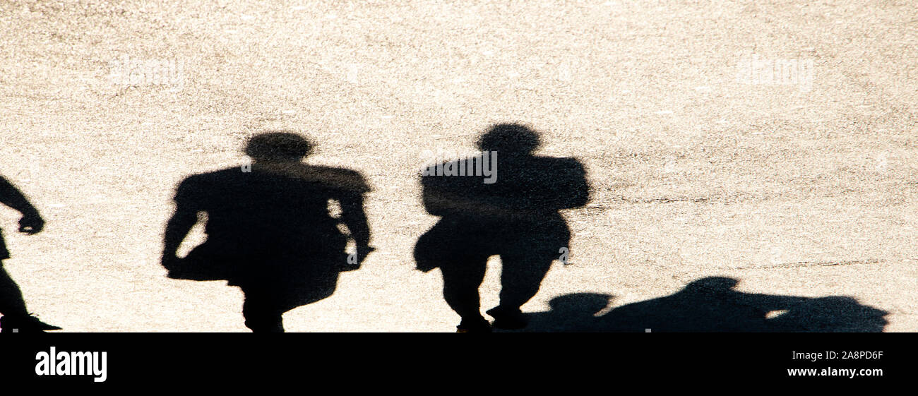 Sfocata ombra silhouette di persone a piedi la città sulla strada pedonale in alto contrasto bianco e nero Foto Stock