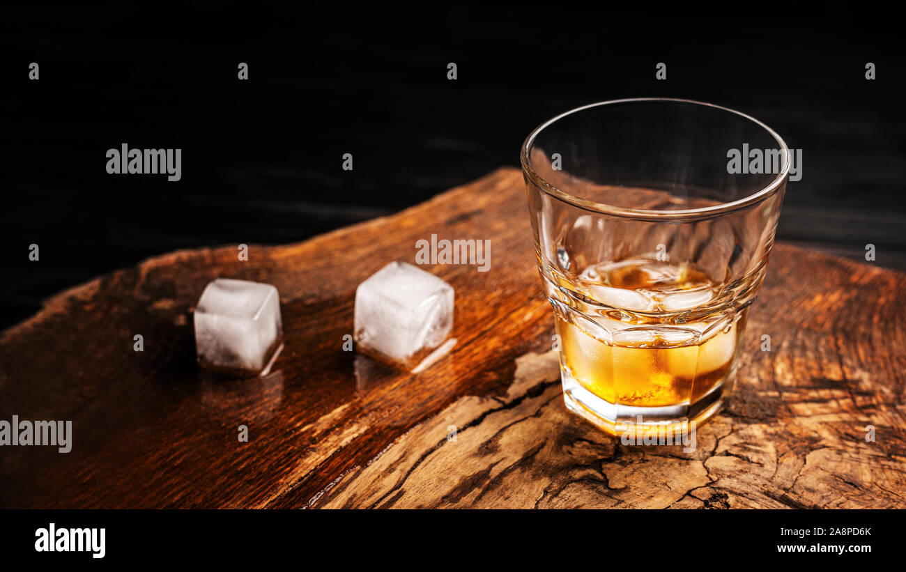 Un bicchiere di bevanda alcolica su un tavolo di legno. Cocktail di whiskey con ghiaccio vista superiore Foto Stock