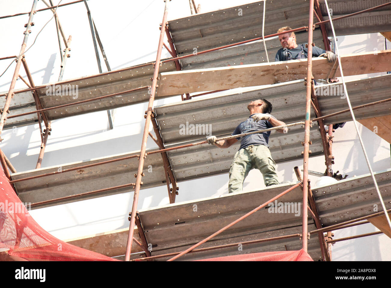 A Belgrado, in Serbia - Ottobre 25, 2019: due sprotetto lavoratori edili sul patibolo durante la facciata del palazzo la ricostruzione, un pericoloso, un pericolo Foto Stock