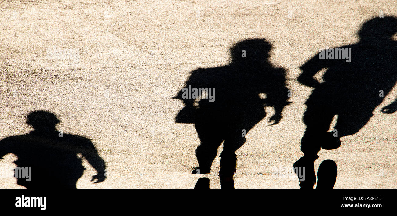 Sfocata ombra silhouette di persone a piedi la città sulla strada pedonale in alto contrasto seppia in bianco e nero Foto Stock