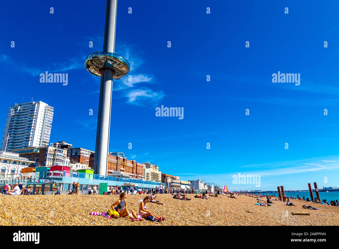 Persone sedute sulla spiaggia con la torre di osservazione Brighton i360 alta 162 metri sul lungomare, Brighton, Regno Unito Foto Stock