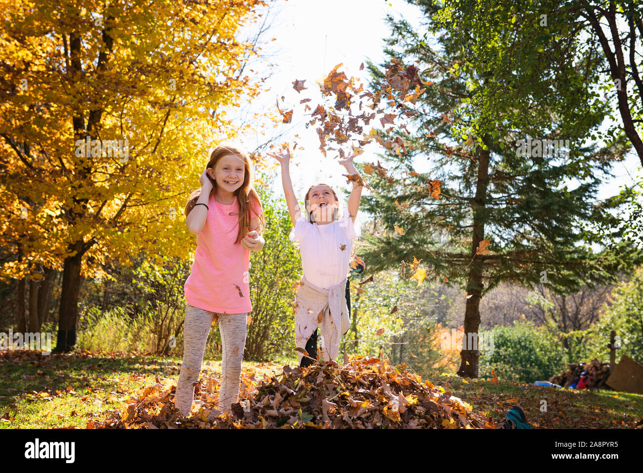 Due giovani ragazze giocando in foglie di autunno Foto Stock