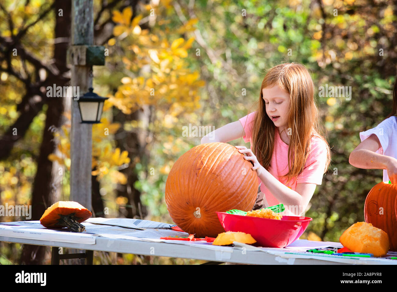 Giovani dai Capelli rossi ragazza intaglia una zucca all'aperto Foto Stock