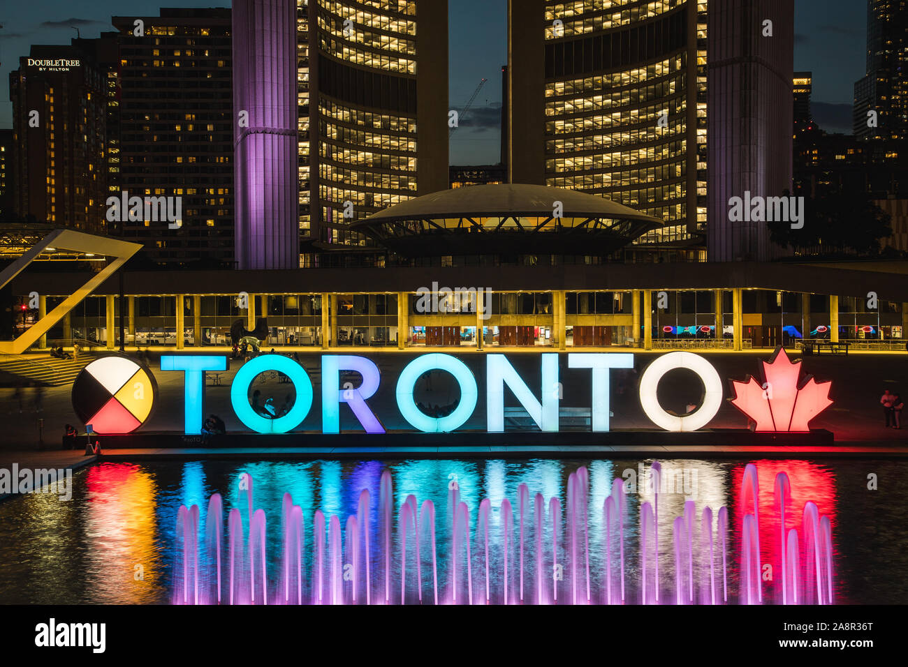 TORONTO, Canada - 17LUGLIO 2019: un primo piano del segno di Toronto a Nathan Phillips Square con il Municipio in background. Scattata di notte. Persone Foto Stock