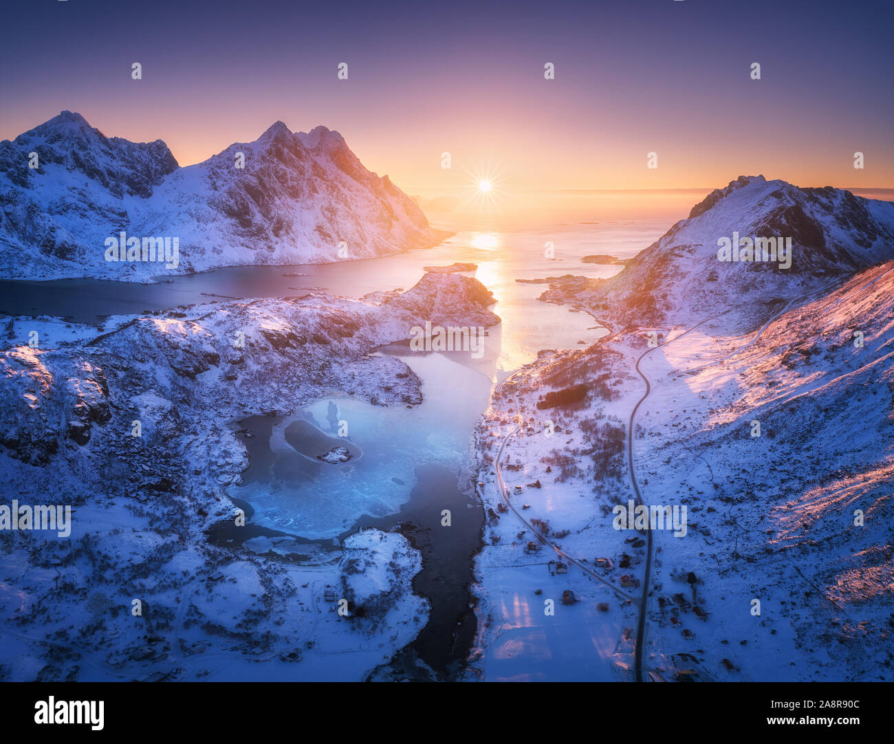 Vista aerea di montagne innevate, mare, cielo viola al tramonto Foto Stock