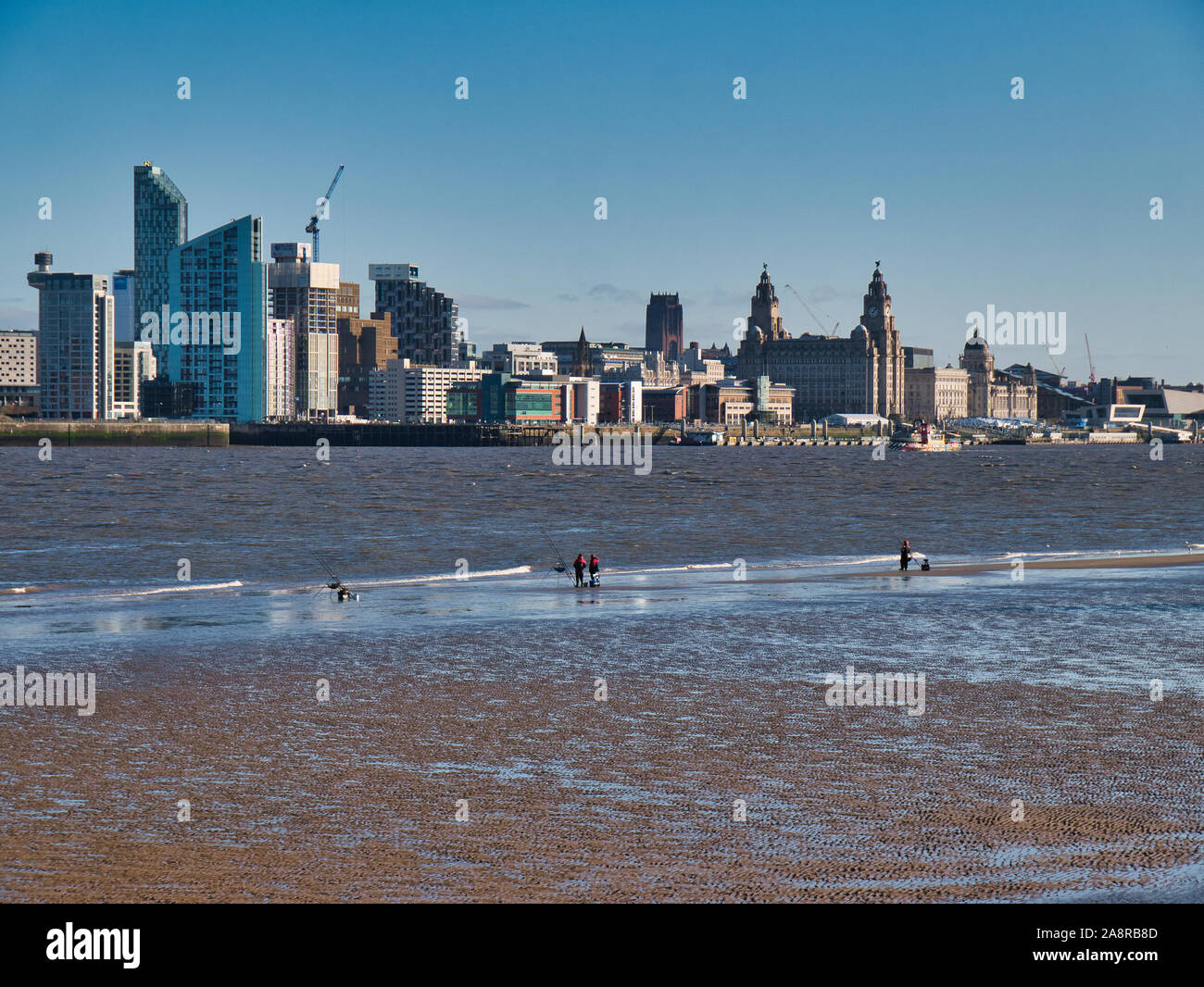 La pesca in mare con la bassa marea nel fiume Mersey con il panorama del centro storico, l'UNESCO elencati Liverpool waterfront su una soleggiata giornata senza nuvole Foto Stock