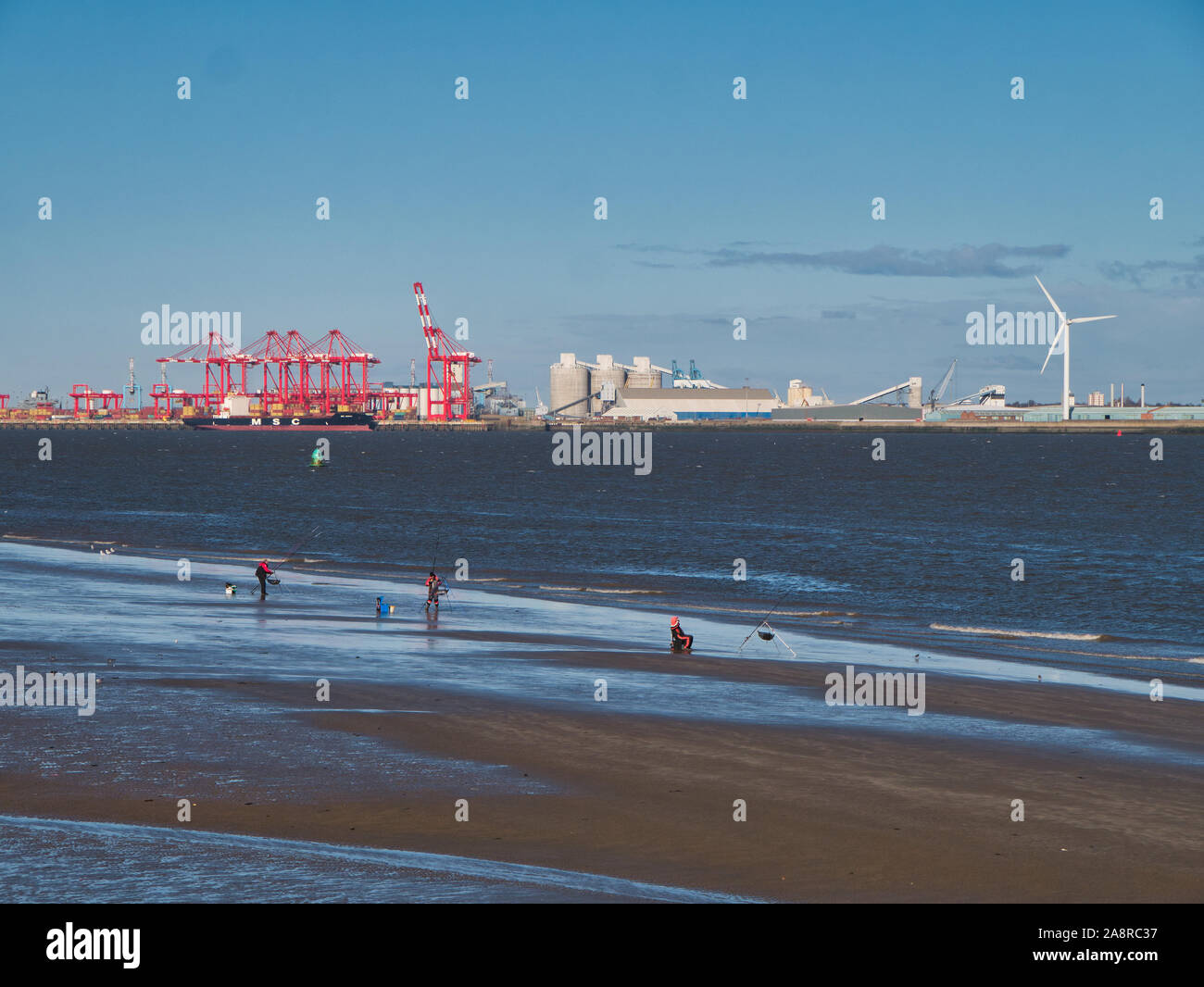 La pesca in mare con la bassa marea nel fiume Mersey con il porto di Liverpool contenitore facility, in background. Foto Stock