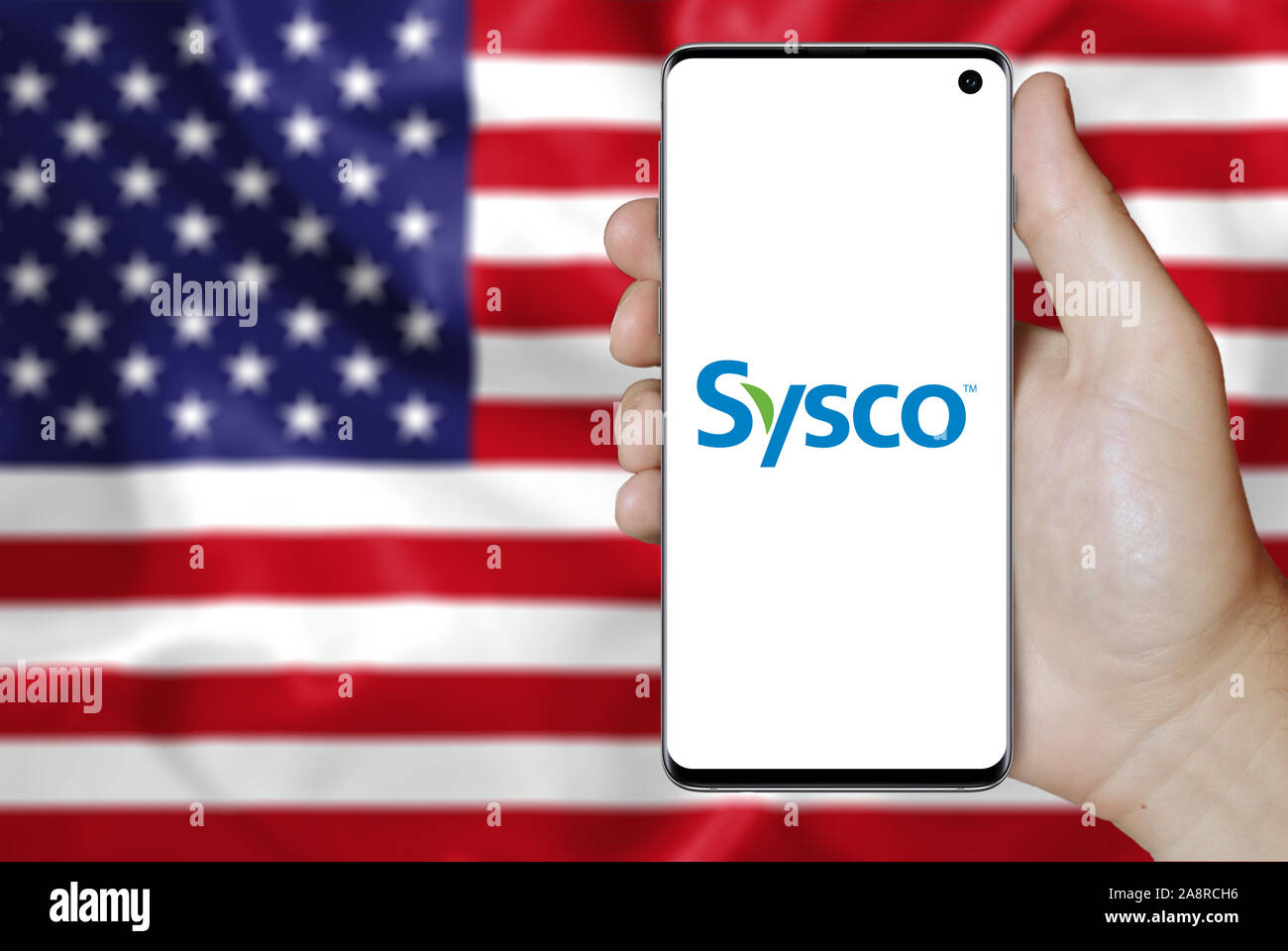 Il logo della società pubblica Sysco Corp. visualizzata su uno smartphone. Bandiera degli Stati Uniti sullo sfondo. Credito: PIXDUCE Foto Stock