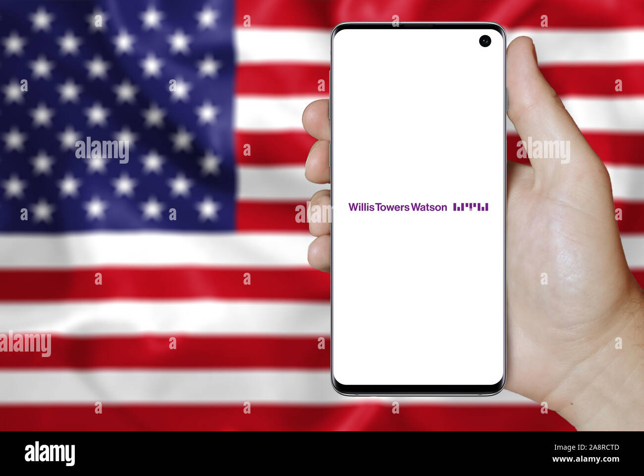 Il logo della società pubblica Willis Towers Watson visualizzata su uno smartphone. Bandiera degli Stati Uniti sullo sfondo. Credito: PIXDUCE Foto Stock