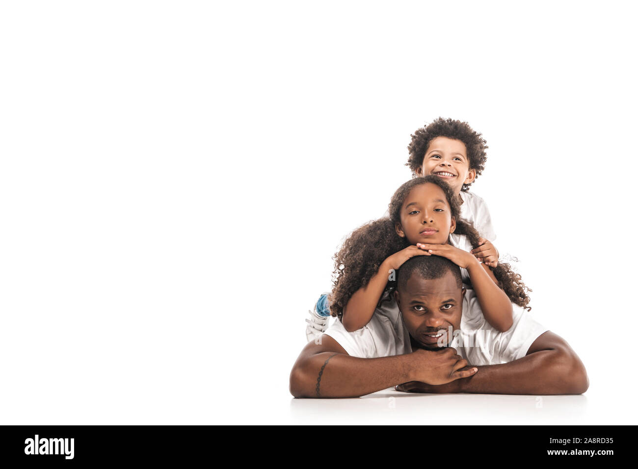 African American la figlia e il figlio avendo divertimento mentre giaceva sul retro dei padri insieme su sfondo bianco Foto Stock