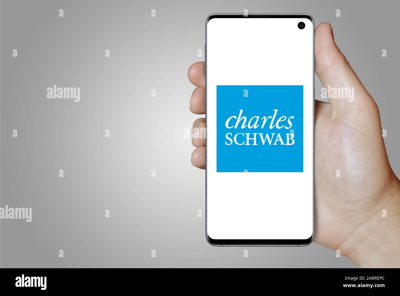 Il logo della società pubblica di Charles Schwab Corporation visualizzata su uno smartphone. Sfondo grigio. Credito: PIXDUCE Foto Stock