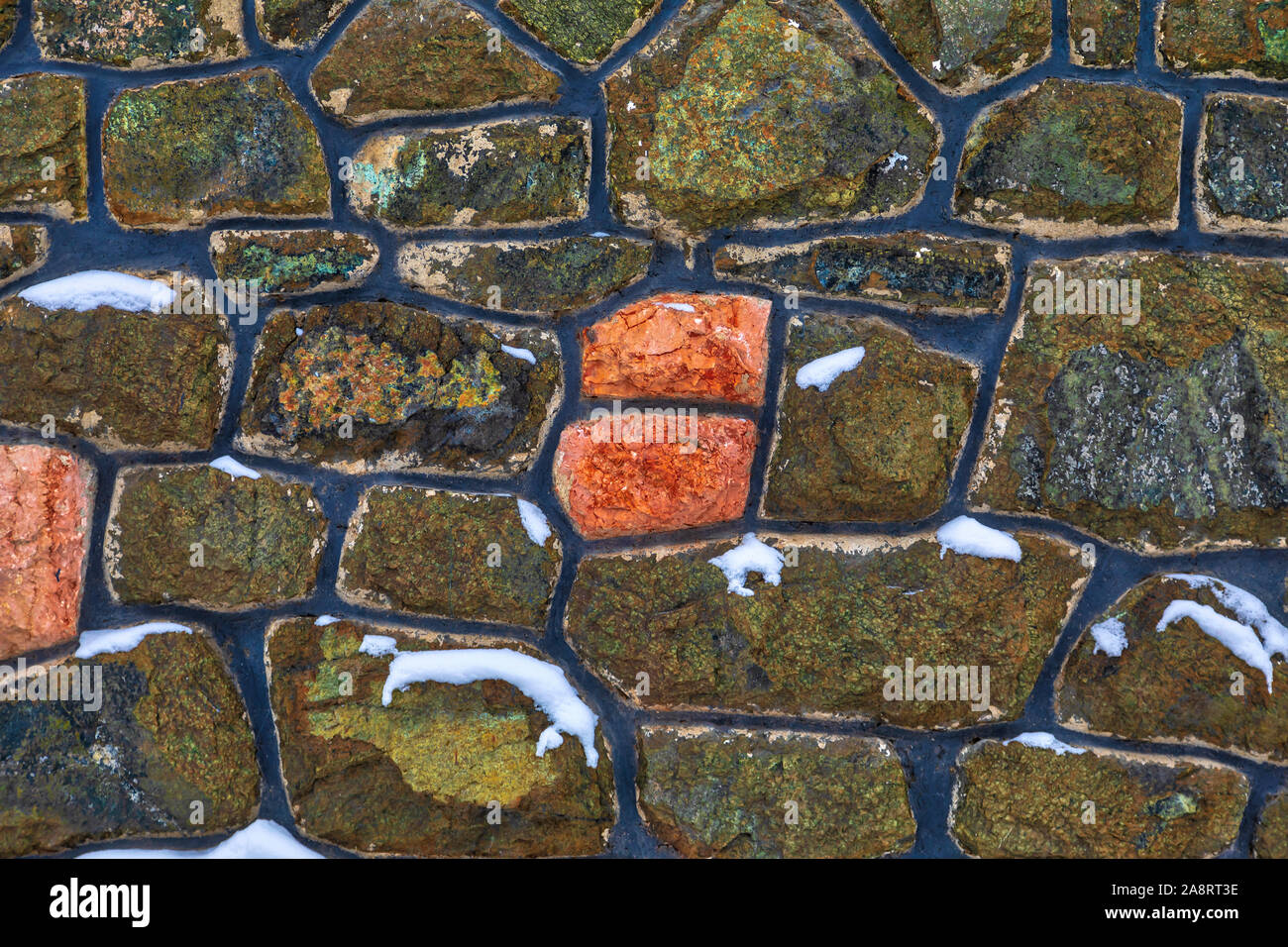 Dettaglio di un coloratissimo congelati stonewall parzialmente coperto di neve. Immagine Foto Stock
