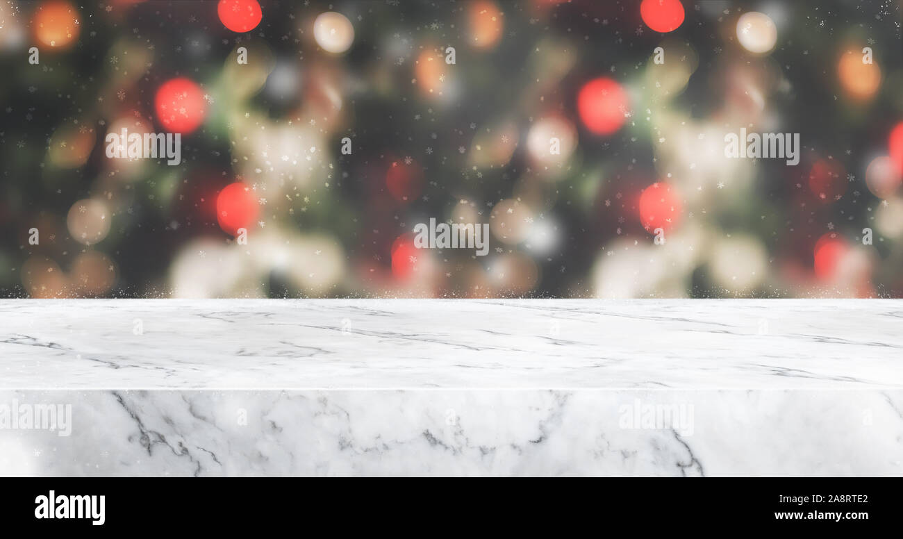 Tavola di marmo alto con sfocatura astratto albero di Natale decorazioni in rosso la sfera e la caduta di neve con sfondo bokeh luce,vacanze inverno sfondo,Mock up banner per Foto Stock