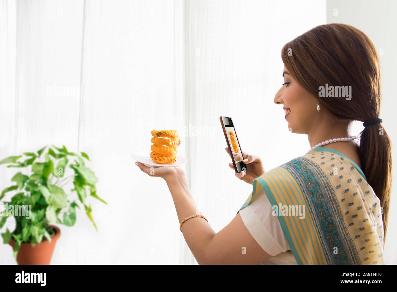 Donna facendo clic su foto del piatto dolce in mano Foto Stock