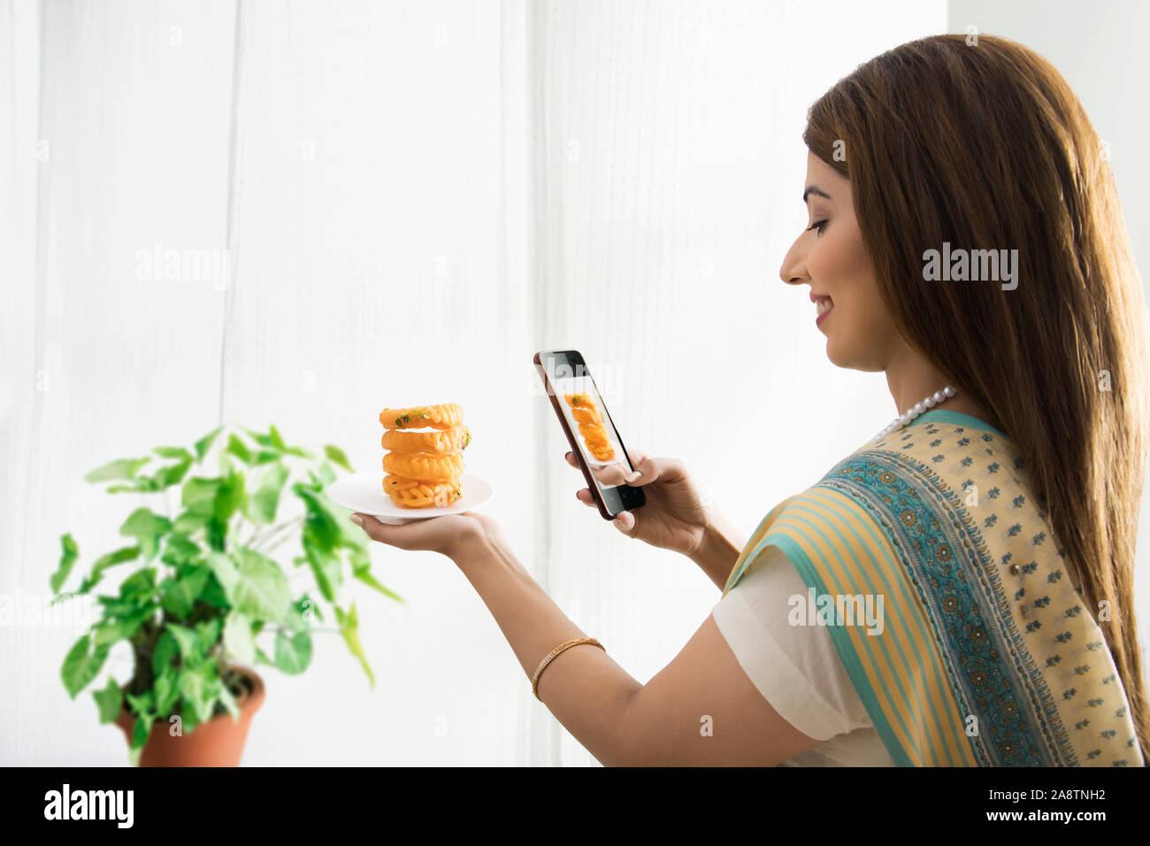 Donna facendo clic su foto del piatto dolce in mano Foto Stock