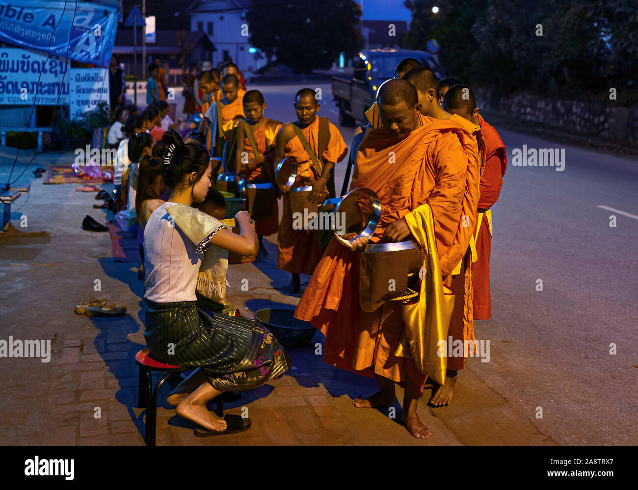 I monaci in abiti dello zafferano nelle strade all'alba nel Patrimonio Mondiale elencati città Luang Prabang in Laos la mattina alms dando cerimonia o Tak Bak Foto Stock