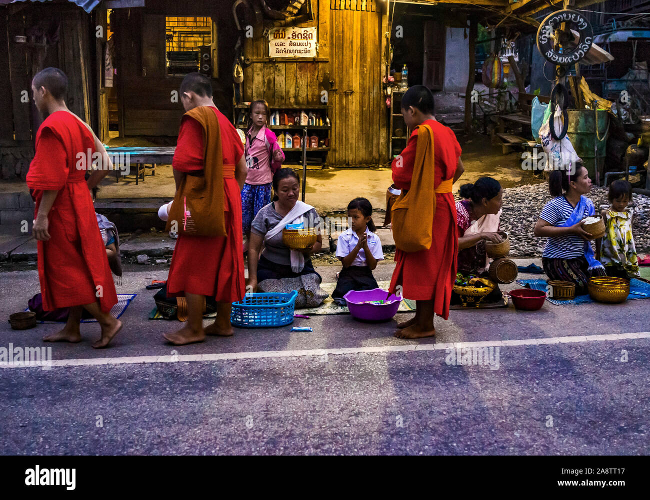 I monaci in abiti dello zafferano nelle strade all'alba nel Patrimonio Mondiale elencati città Luang Prabang in Laos la mattina alms dando cerimonia o Tak Bak Foto Stock