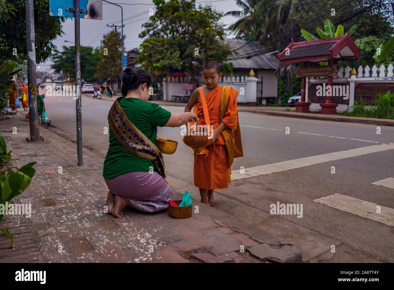 I monaci in abiti dello zafferano nelle strade all'alba nel Patrimonio Mondiale elencati città Luang Prabang in Laos la mattina alms dando cerimonia o Tak Bak Foto Stock