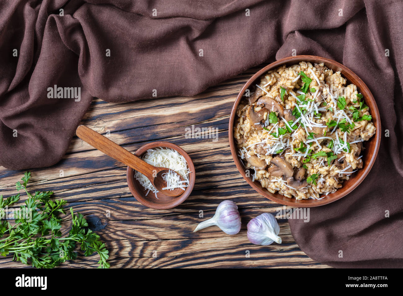 Stile rustico di funghi selvatici cremoso risotto con parmigiano grattugiato in un recipiente di terracotta, vista da sopra, flatlay Foto Stock