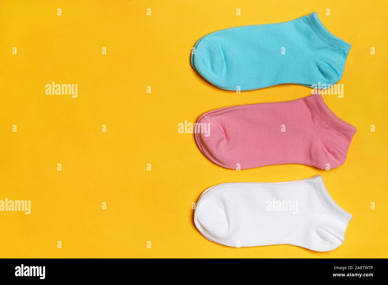 Primo piano set di calze corte in bianco, rosa, blu su sfondo giallo con copia spazio. Foto Stock