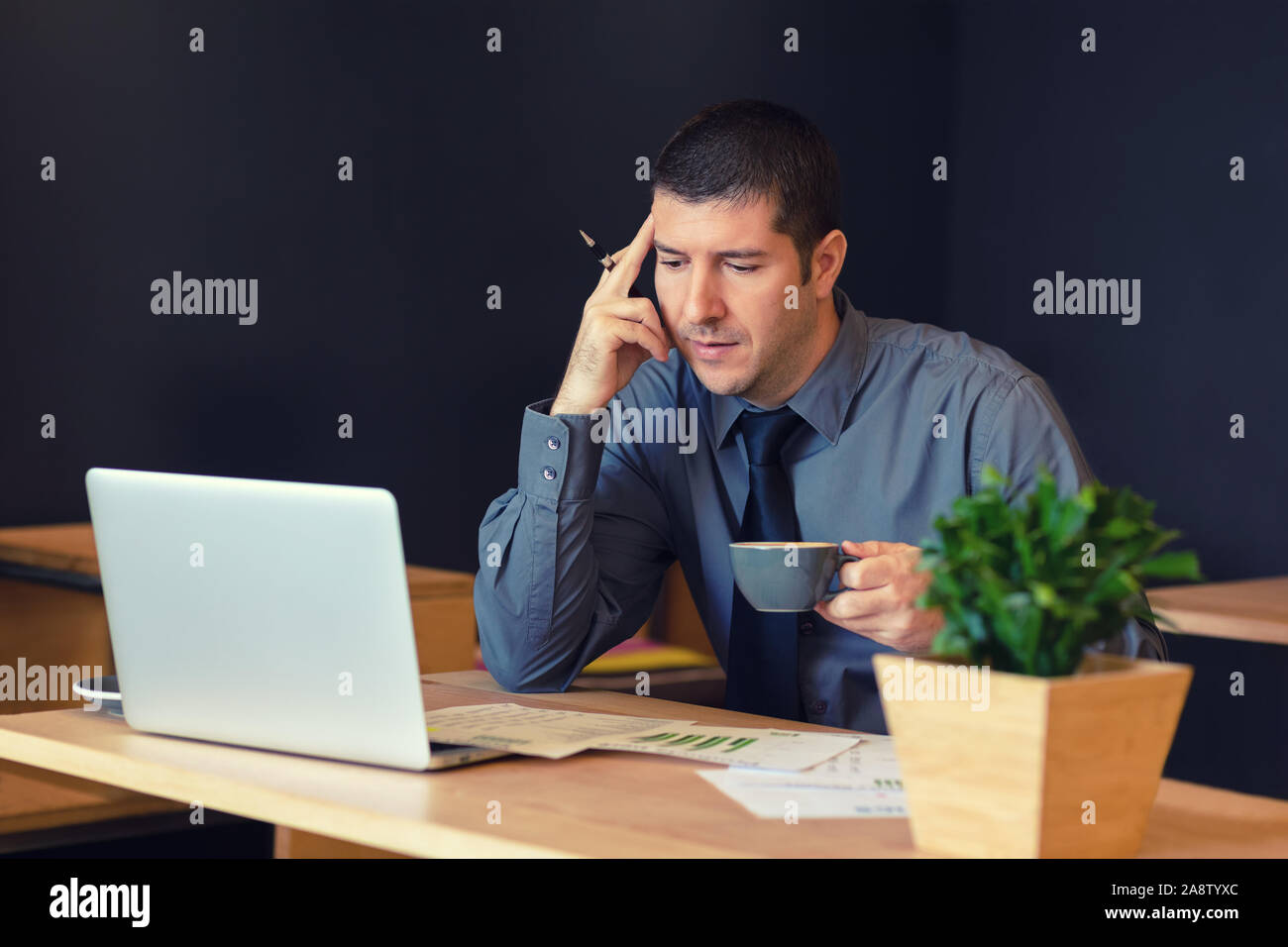 Imprenditore pensieroso seduta a tavola nella caffetteria alla moda il lavoro in remoto sul computer portatile Foto Stock