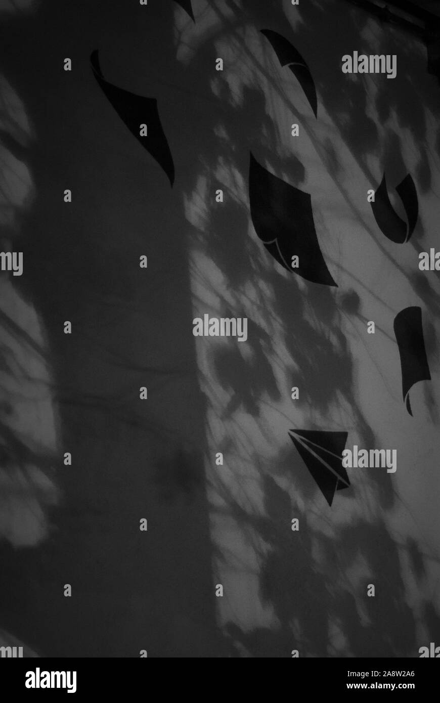 Fogli di carta trasportati dal vento, disegnato su una parete, fra la notte  di luci e di ombre, presi in bianco e nero Foto stock - Alamy