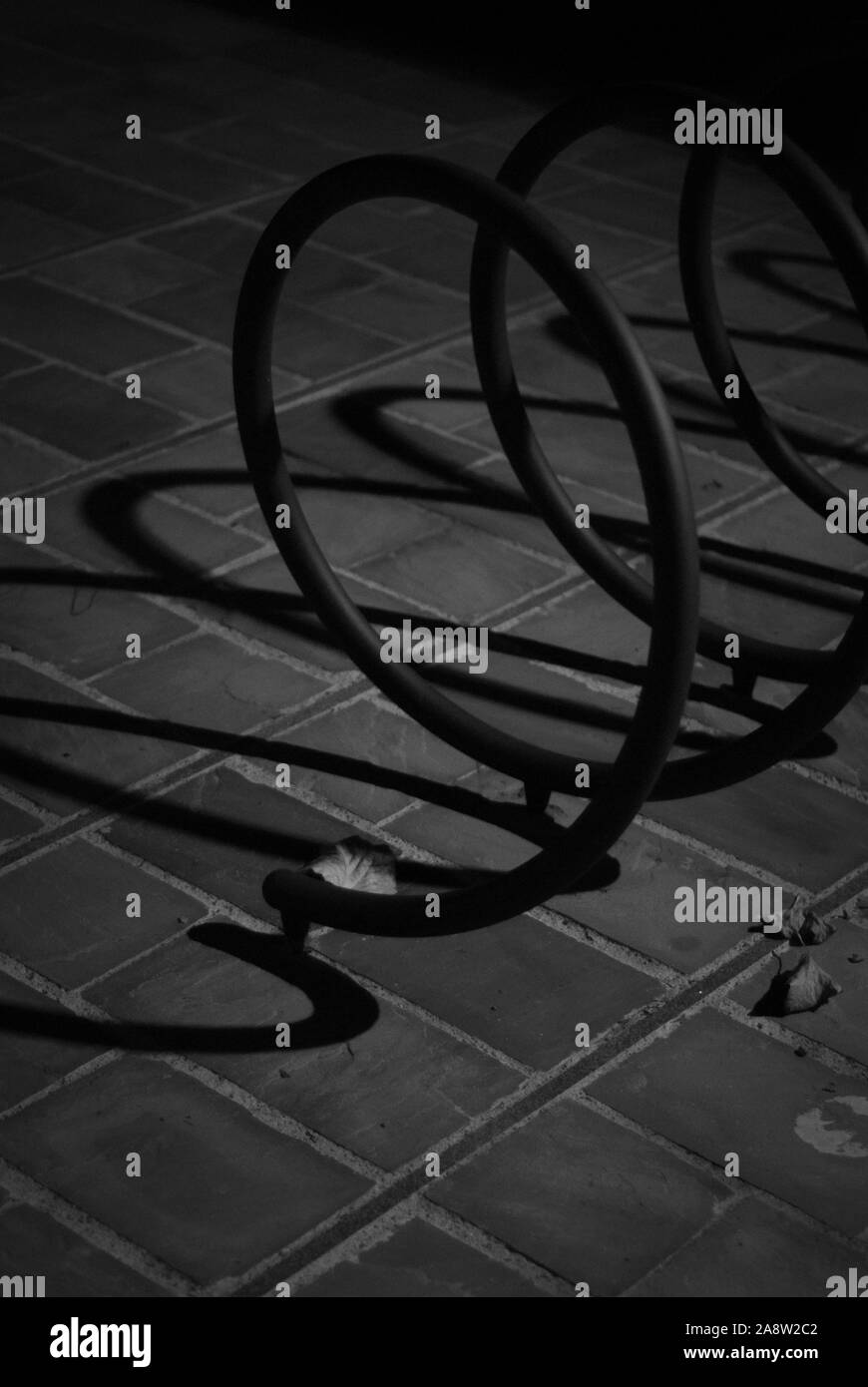 Dettaglio di un supporto a spirale per biciclette, girato in bianco e nero, durante l'autunno Foto Stock