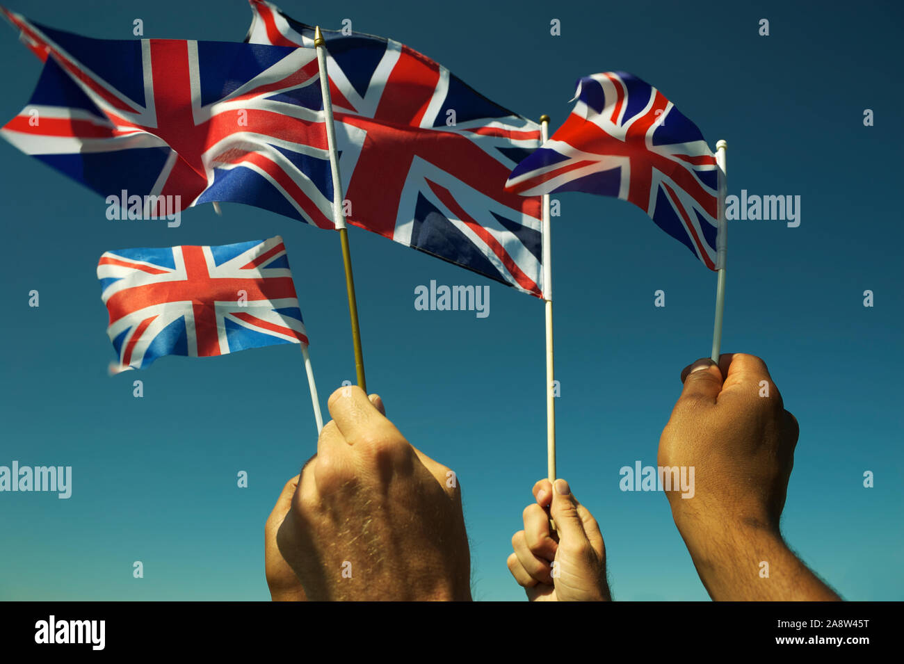 Gruppo di mani patriottici sventolando Union Jack Flag britannico in blu luminoso cielo a una protesta Brexit a Londra Foto Stock