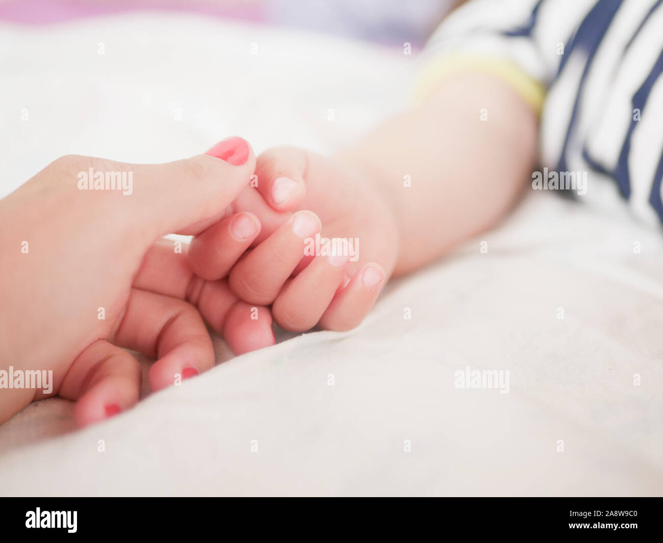 La mamma tiene per mano un bambino di neonato. Close-up. Un luogo per scrivere. Immissione testo. di defocalizzazione. Baby la mano che tiene le dita per mom. Foto Stock