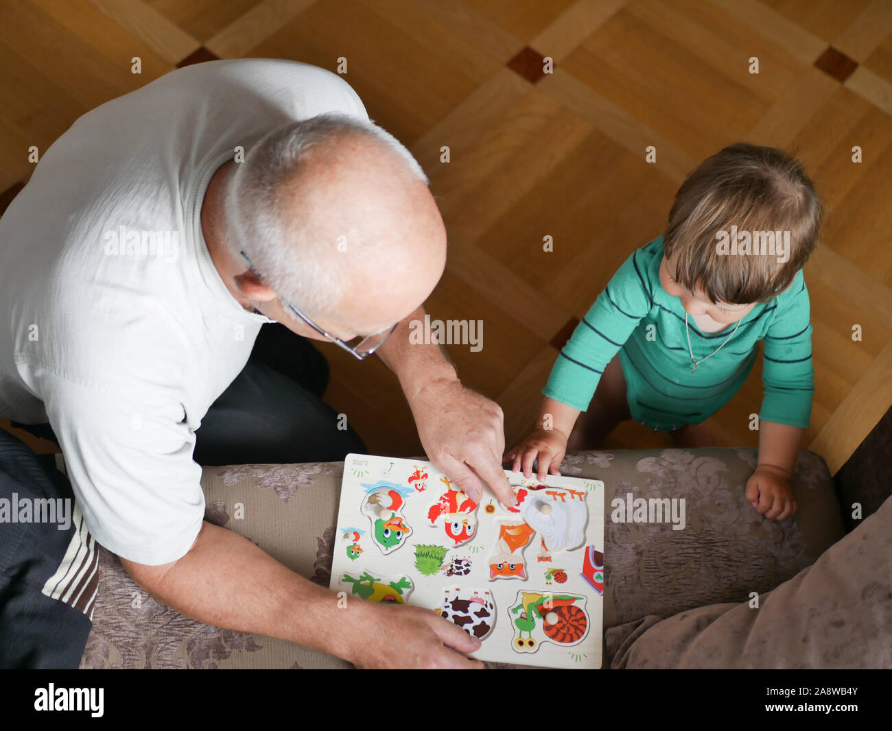Nonno gioca con la sua nipote a casa. Nonno e nipote giocare con giocattoli a casa. Relazioni familiari tra nonno e nipote Foto Stock