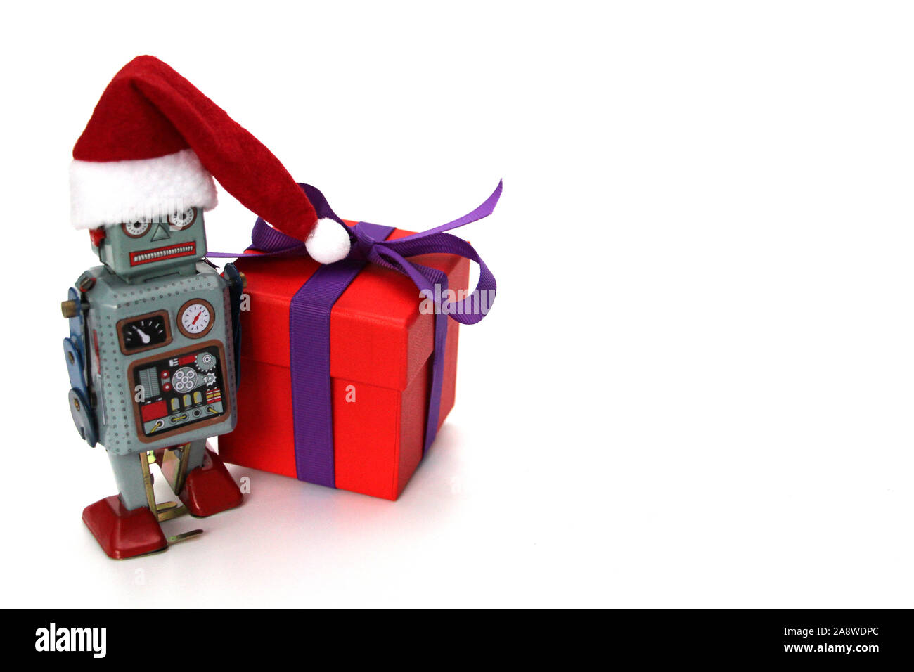 Robot retrò con un grande regalo. Il robot ha un cappello da Babbo Natale. Natale e Anno Nuovo concetto di celebrazione nel robot retrò stile. Sfondo bianco. Foto Stock