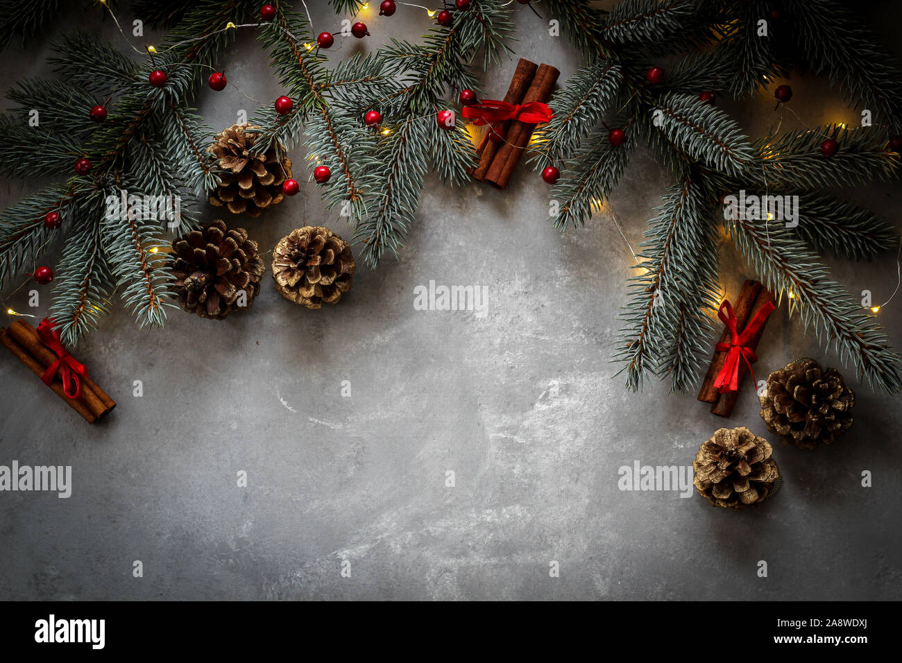 Natale umore confine con abete rami, coni e bastoncini di cannella con dettagli rosso e un spazio di copia Foto Stock