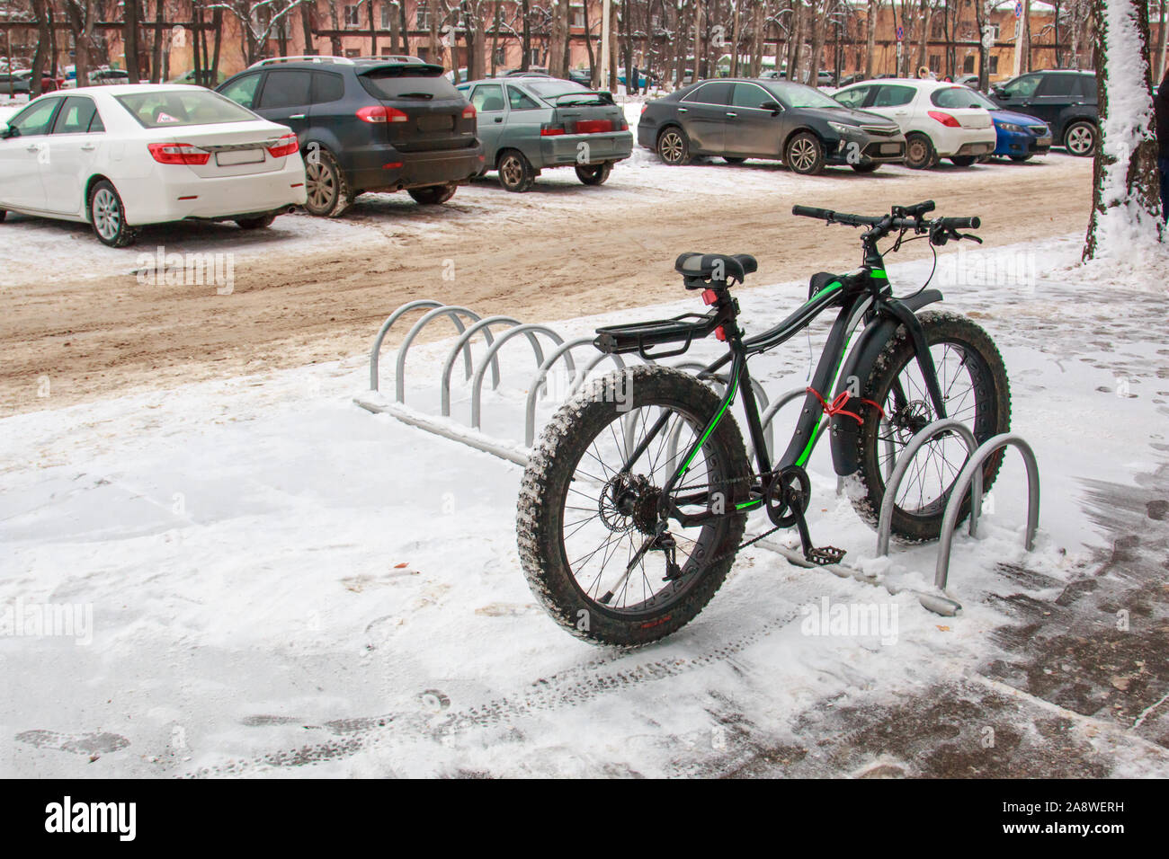 Bicicletta con una vasta gomma nel parcheggio vicino al negozio in città in inverno vicino. Foto Stock