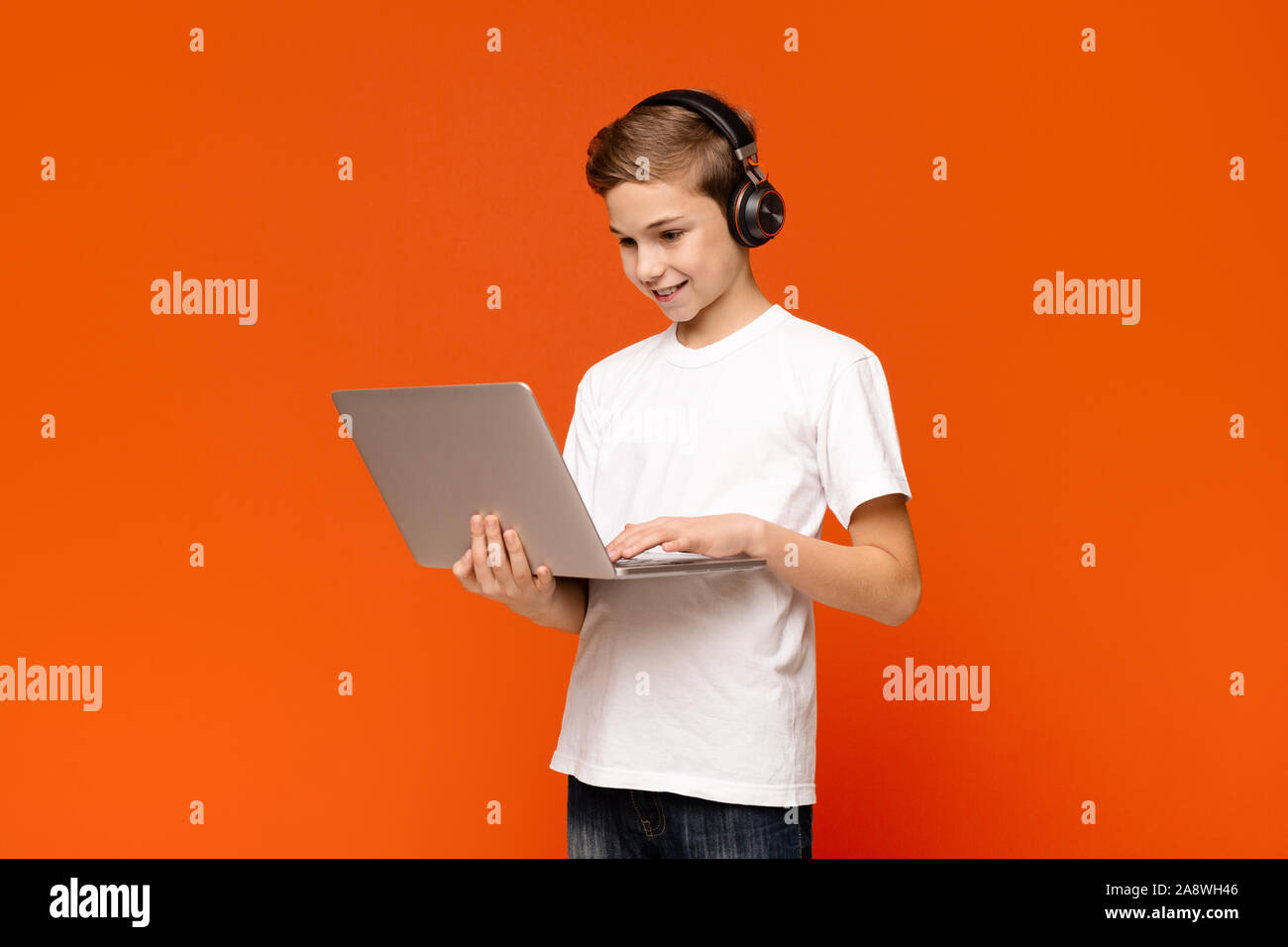 Ragazzo adolescente nelle cuffie la riproduzione del video gioco sul computer portatile Foto Stock