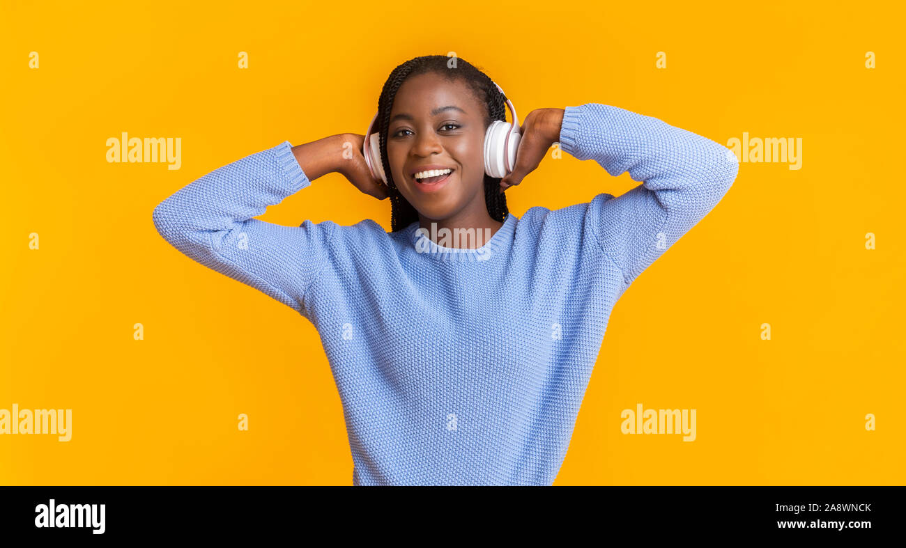 Emotional ragazza nera con cuffie per ascoltare musica e canto Foto Stock