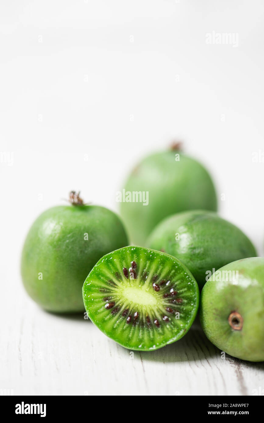 Primo piano di alcuni maturi frutti di bosco kiwi su un bianco tavolo rustico contro uno sfondo bianco con un po' di spazio vuoto sulla parte superiore Foto Stock