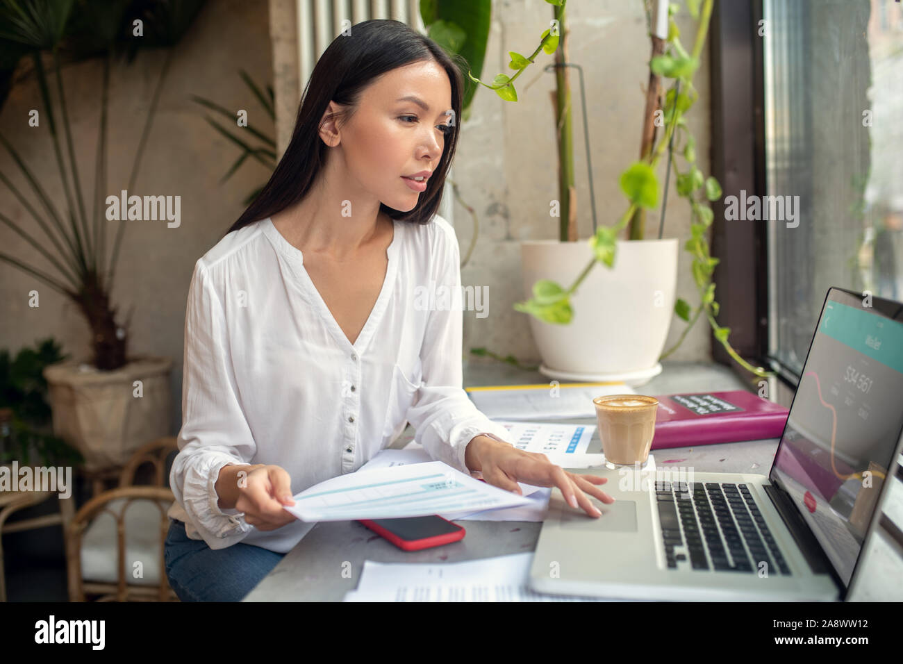 Imprenditrice di occupato tramite computer portatile durante la compilazione della dichiarazione fiscale Foto Stock