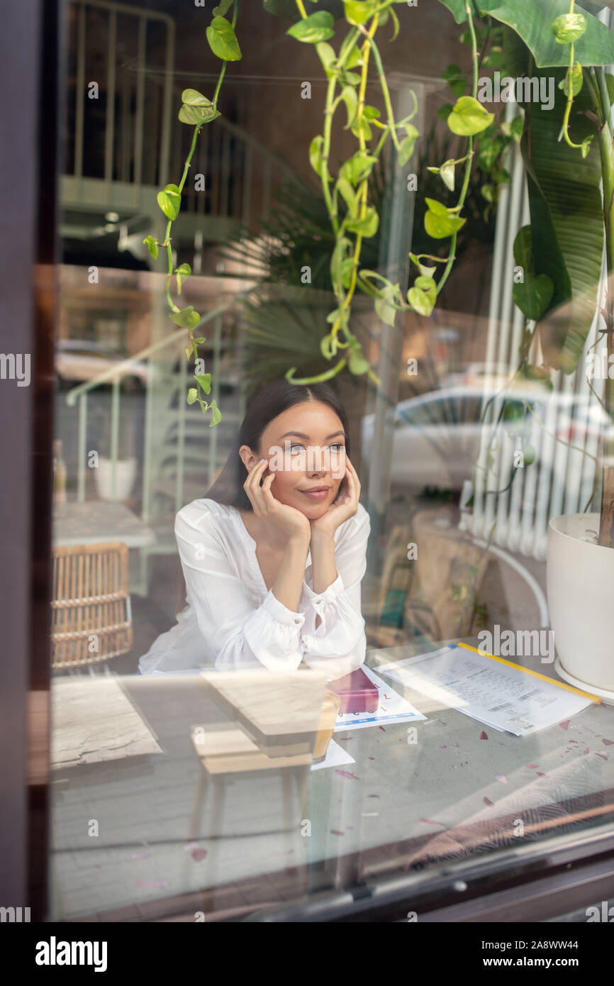 Sentimento donna annoiati durante l'attesa per il collega in caffetteria Foto Stock