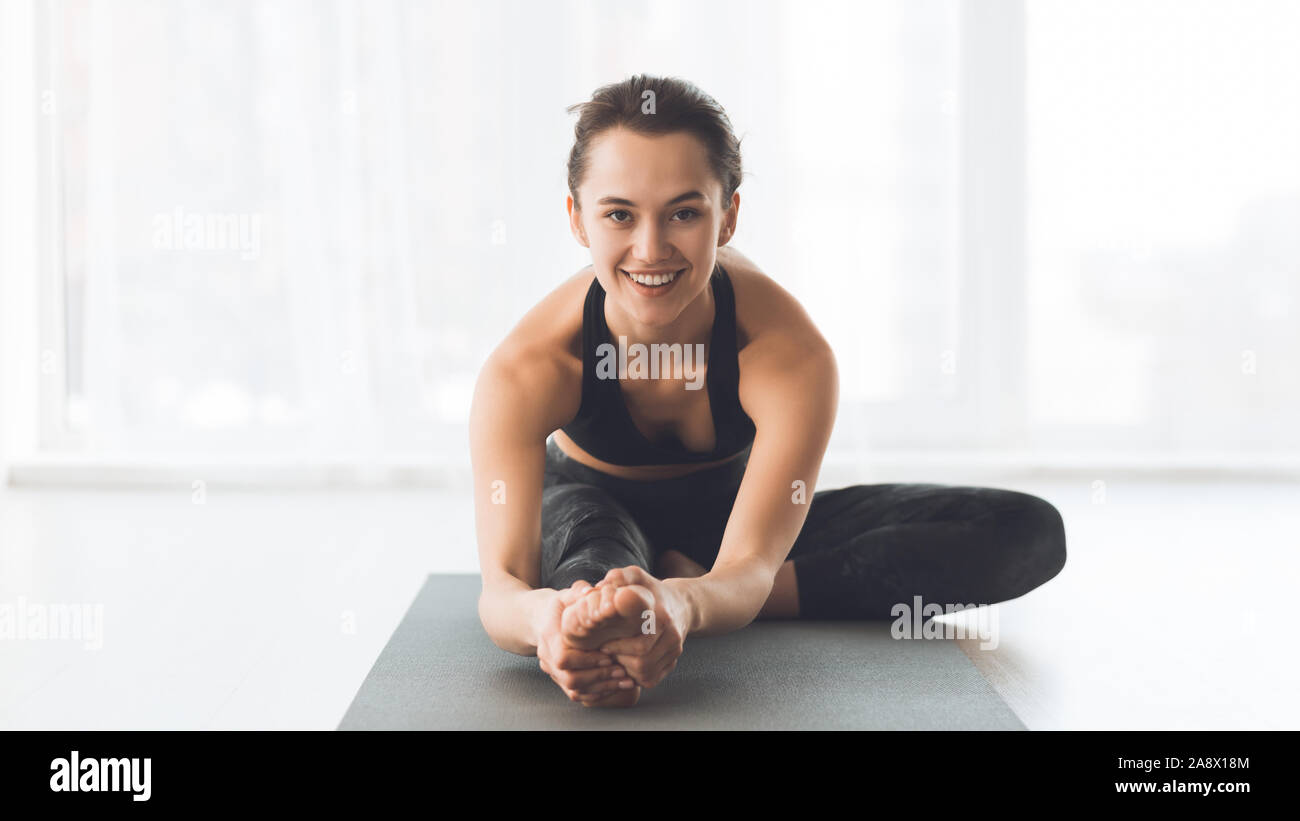 Felice fit donna stretching gambe, formazione in studio di luce Foto Stock