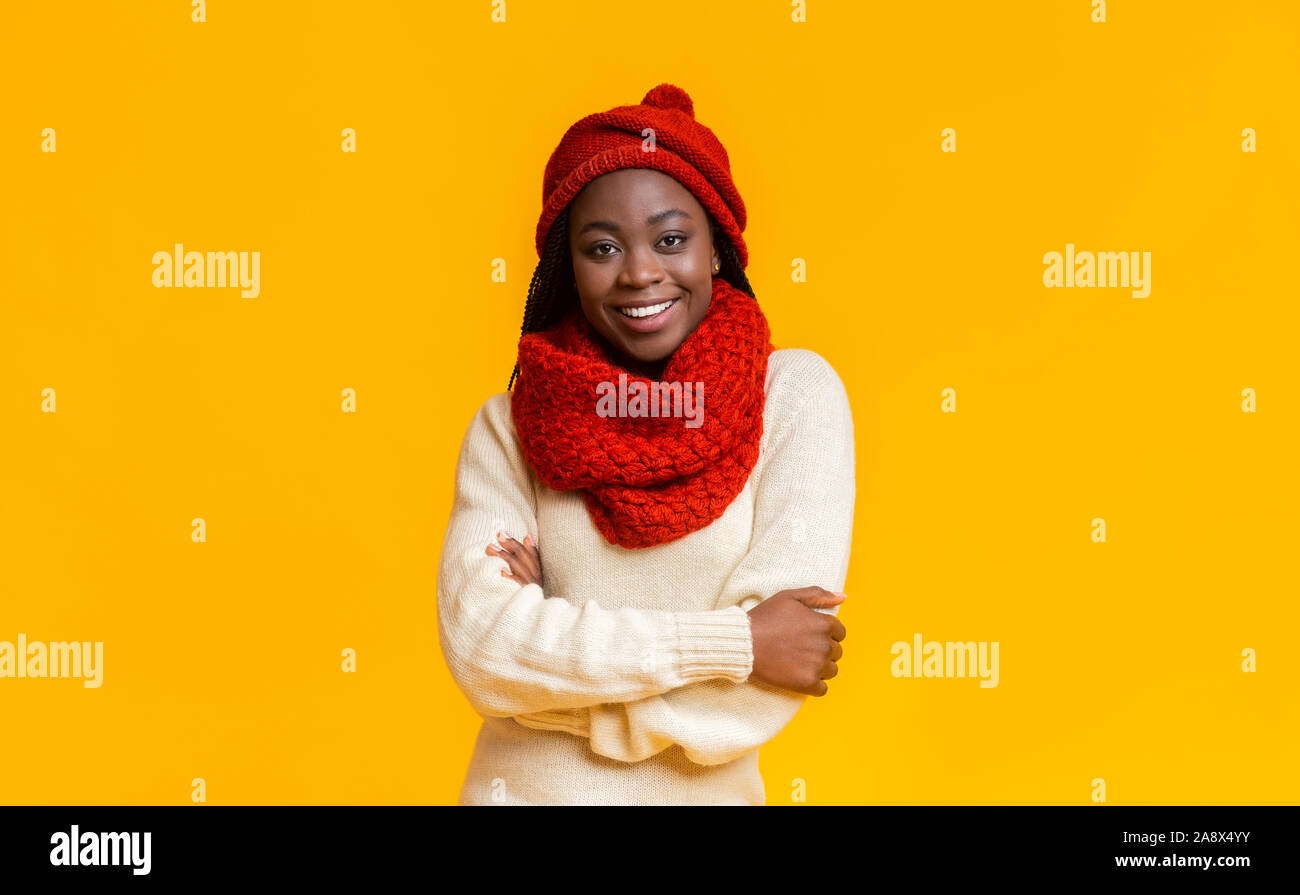 Fiducioso inverno nero ragazza sorridente su giallo di sfondo per studio Foto Stock
