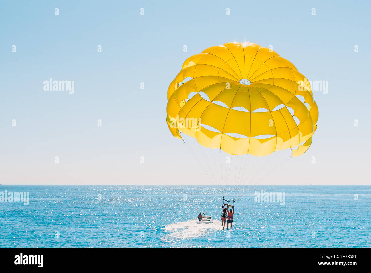 Passatempo divertente in mare - parasailing con persone legate ad una barca Foto Stock