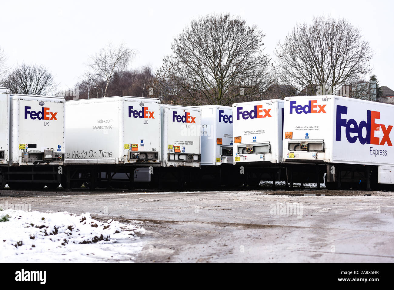 Fed Ex autocarri pronto avente la manutenzione e di essere caricato con i pacchi che devono essere consegnati in tutto il paese e il mondo, veicoli pesanti, logistica Foto Stock