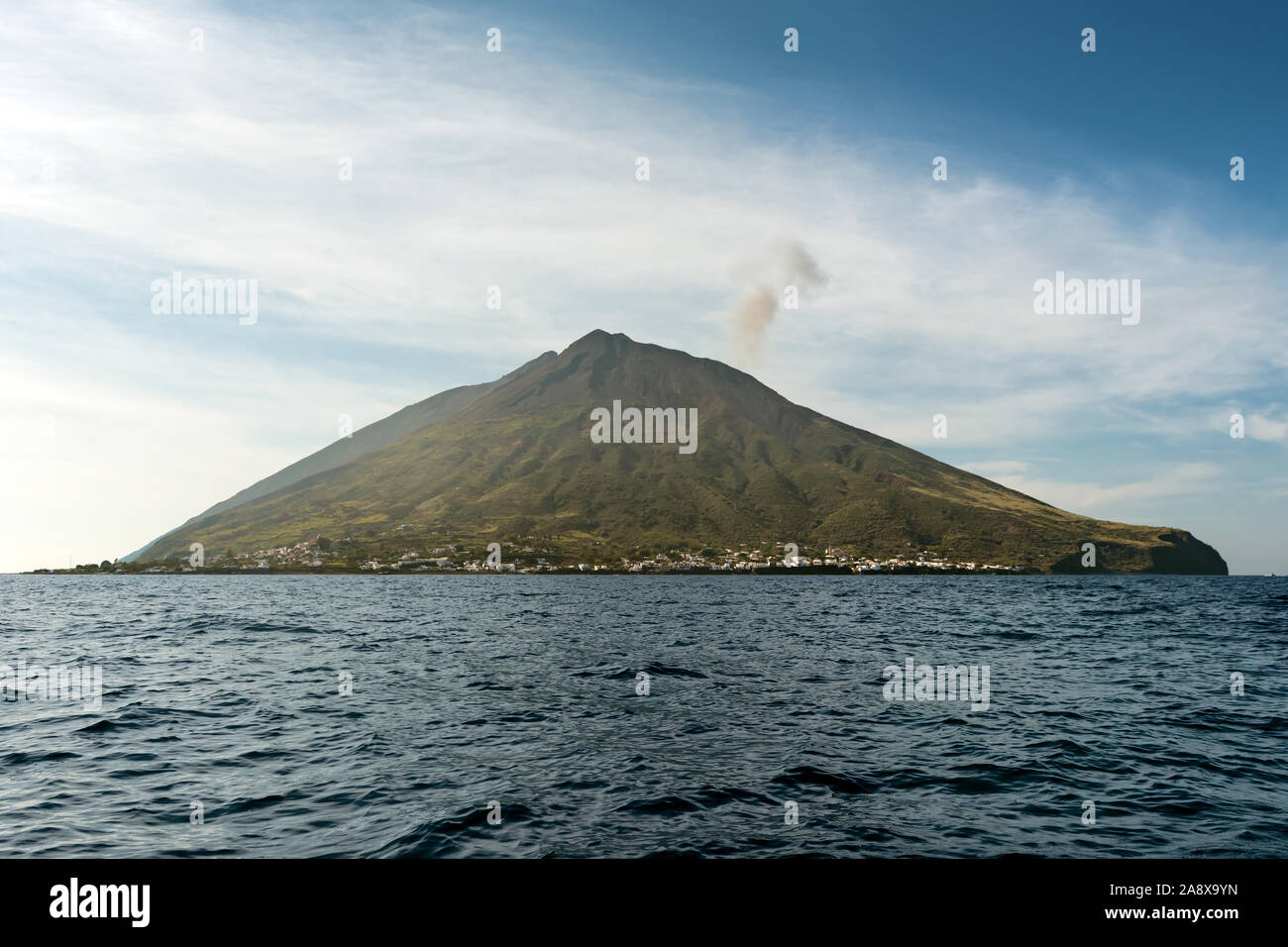 Il attivo vulcano Stromboli nord est lato abitato, giorno shot, blu cielo nuvoloso,sfondo delle Eolie, in Sicilia, Italia. Foto Stock